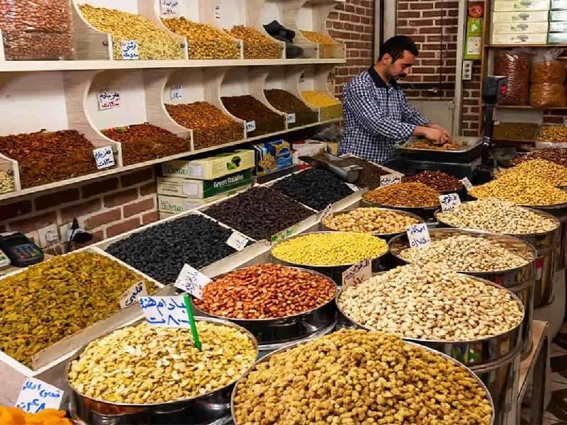 یک فروشنده در مغازه آجیل و خشکبار در حال آماده کردن سفارش مشتری است